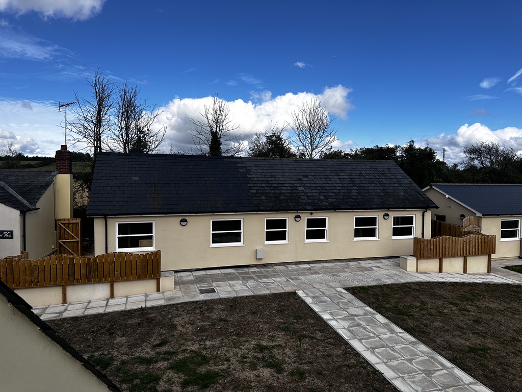 Completed bungalow with cream render and slate roof